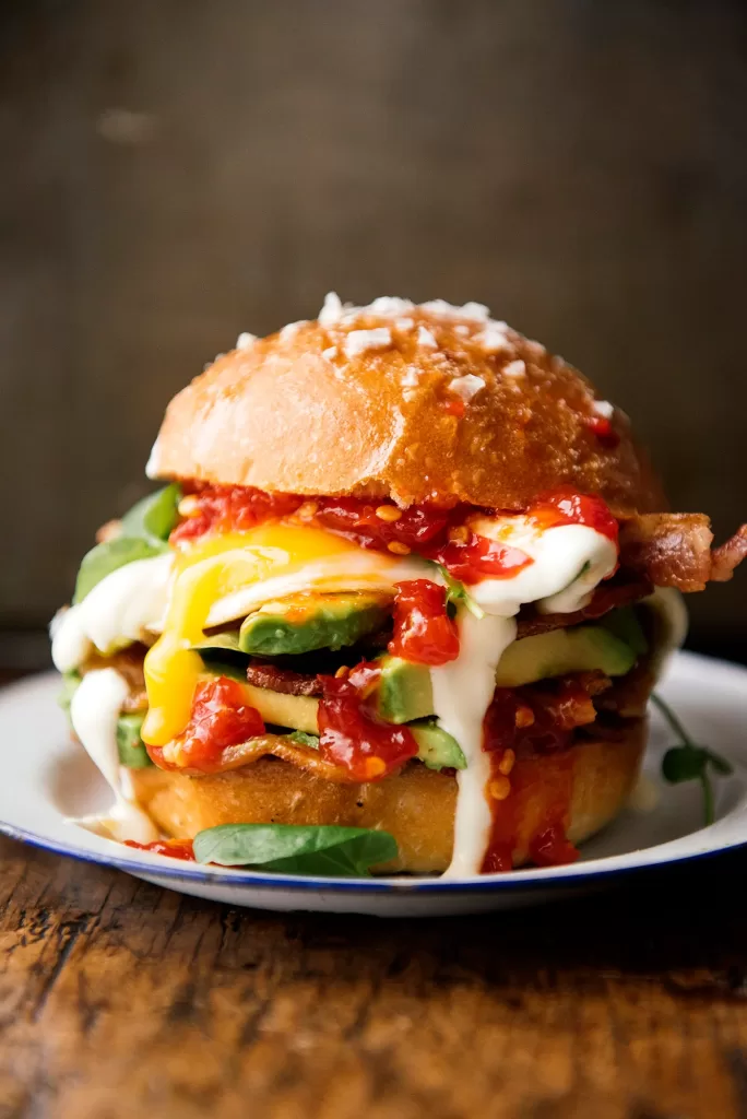 Breakfast burger with avocado, soft eggs, bacon, yoghurt sauce and chilli jam