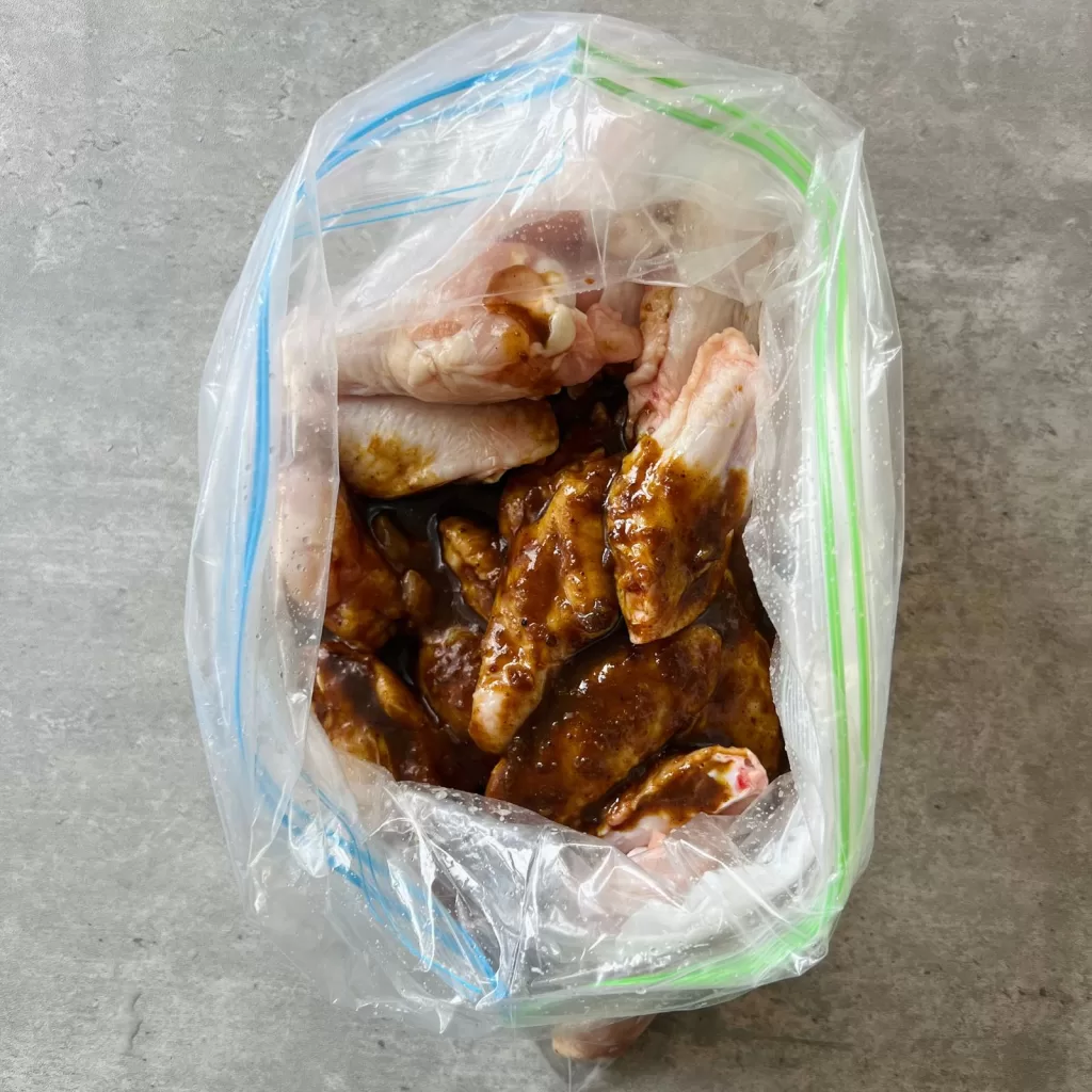 Satay marinade being added to chicken wings in a zip lock bag