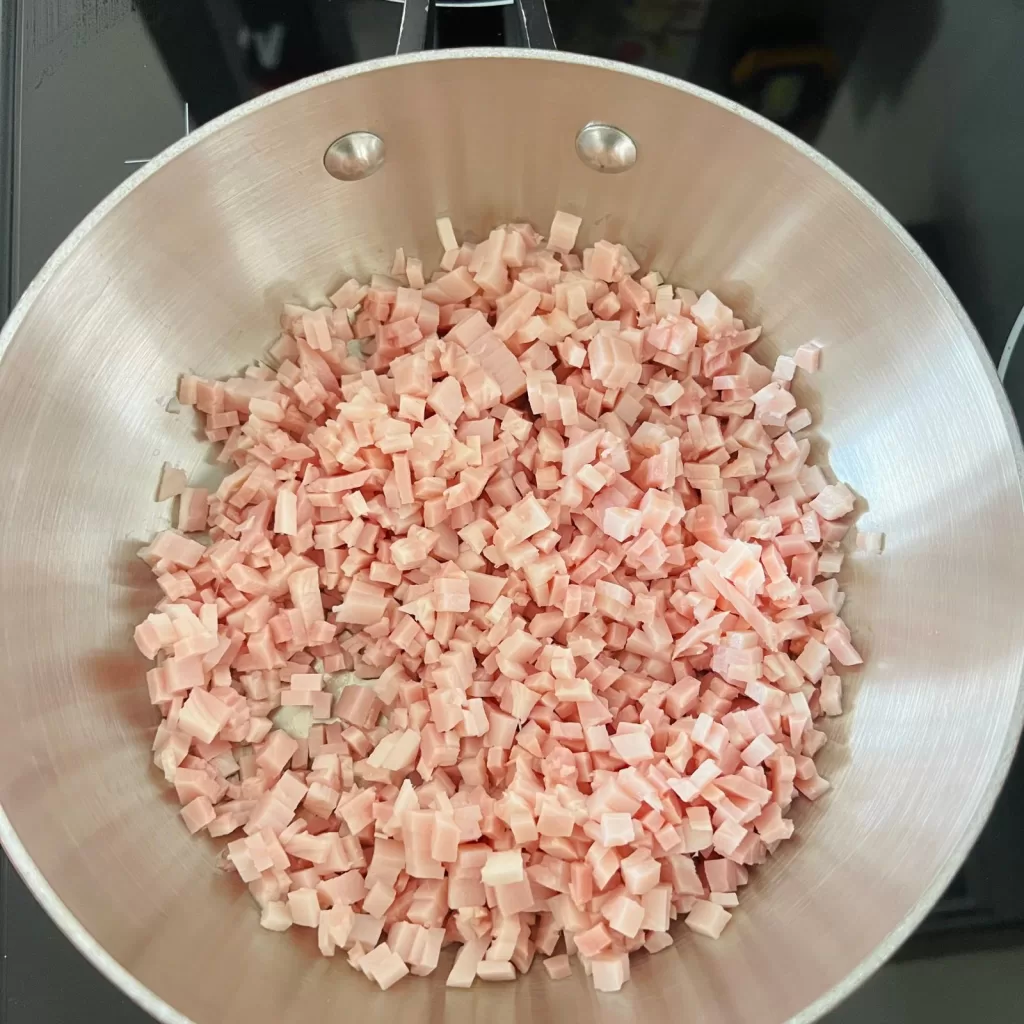 Diced bacon cooking in a saucepan to start tomato bacon and chilli jam