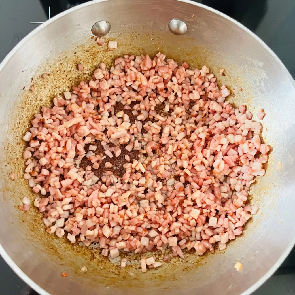 Bacon rendering and lightly browning in a saucepan for savoury bacon jam