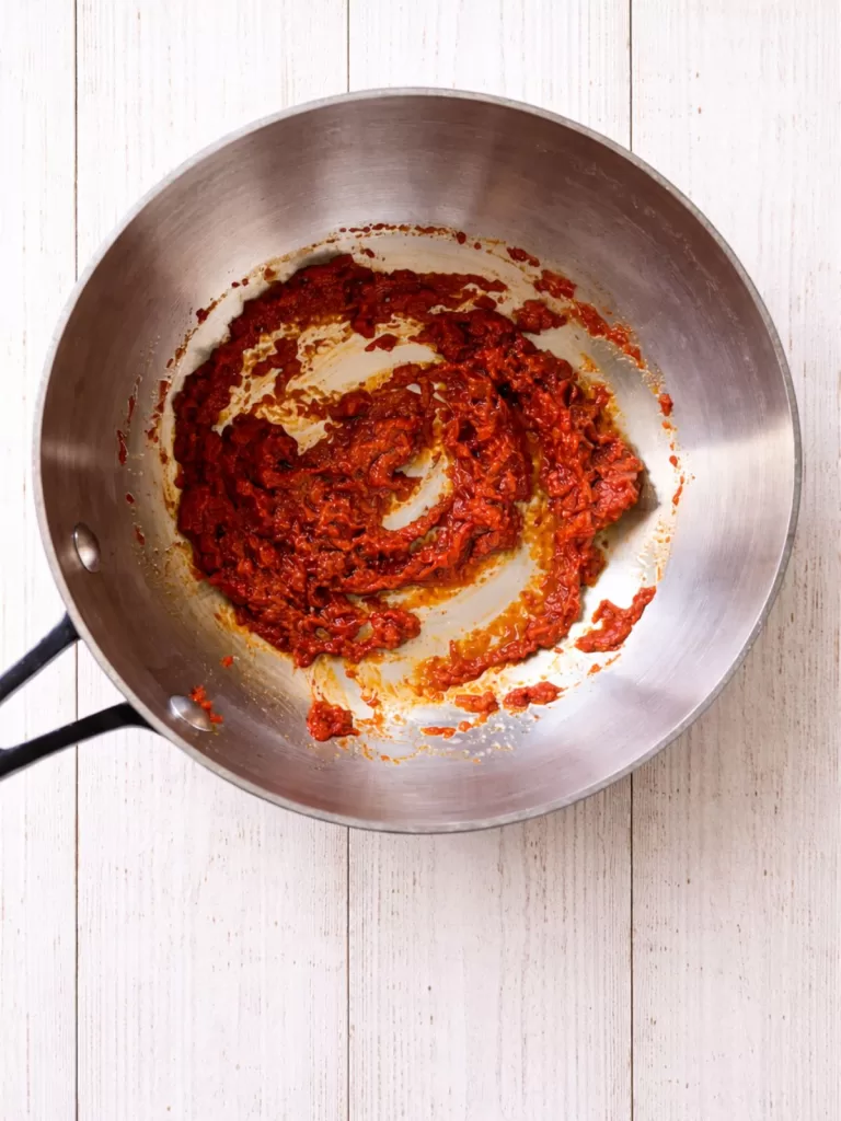 Cooking panang curry paste in a saucepan