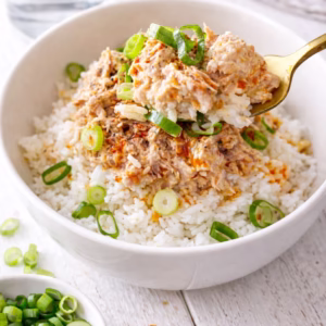 Tuna rice bowl with creamy tuna, chilli oil, and spring onion on jasmine rice, with a spoon lifting a bite. Quick 5 minute meal.