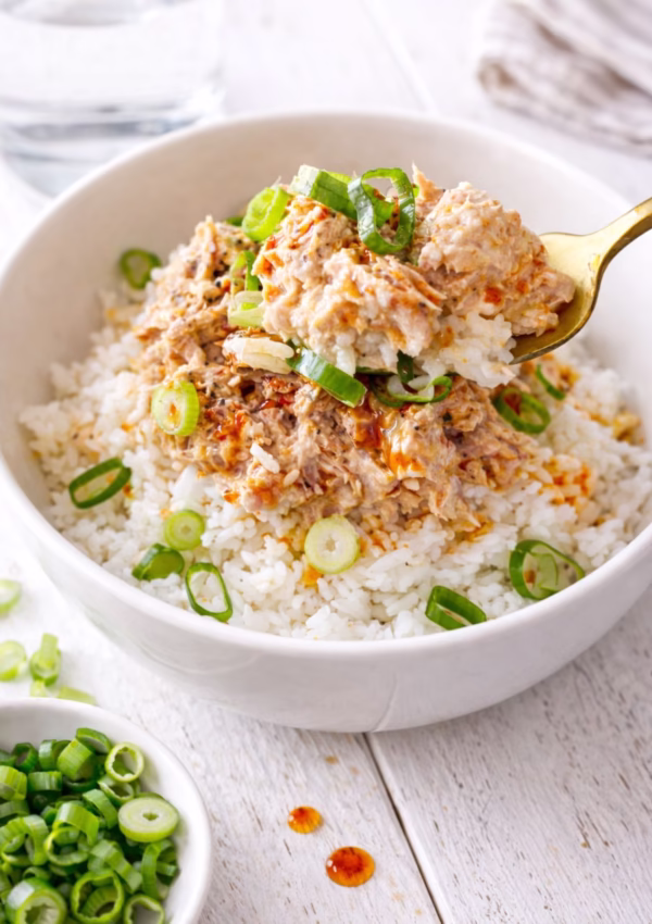 Tuna rice bowl with creamy tuna, chilli oil, and spring onion on jasmine rice, with a spoon lifting a bite. Quick 5 minute meal.