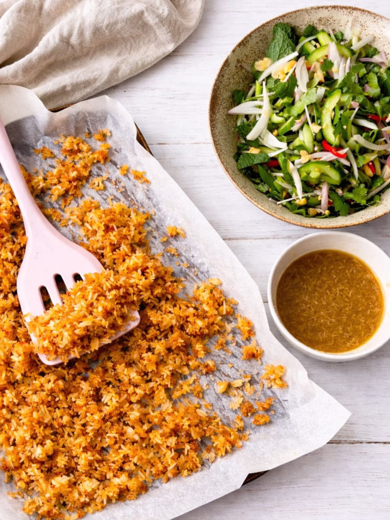 Crispy rice on a baking tray with Thai herb salad and lime dressing ready to assemble