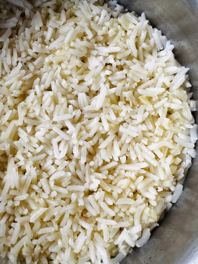 Fluffy garlic butter rice in a saucepan showing separate grains after cooking.