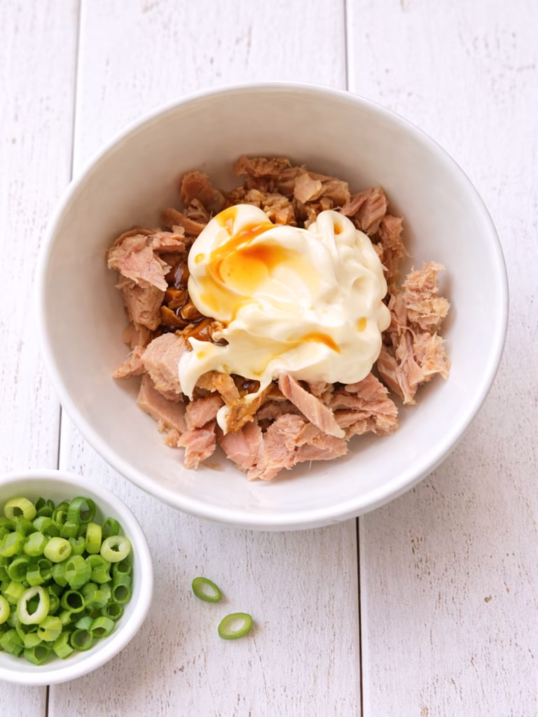 Tuna with mayonnaise and soy sauce in a bowl on a white timber table