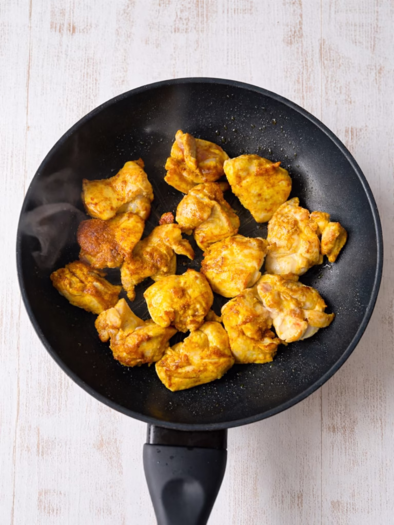 Browning chicken pieces in a pan for slow cooker satay chicken