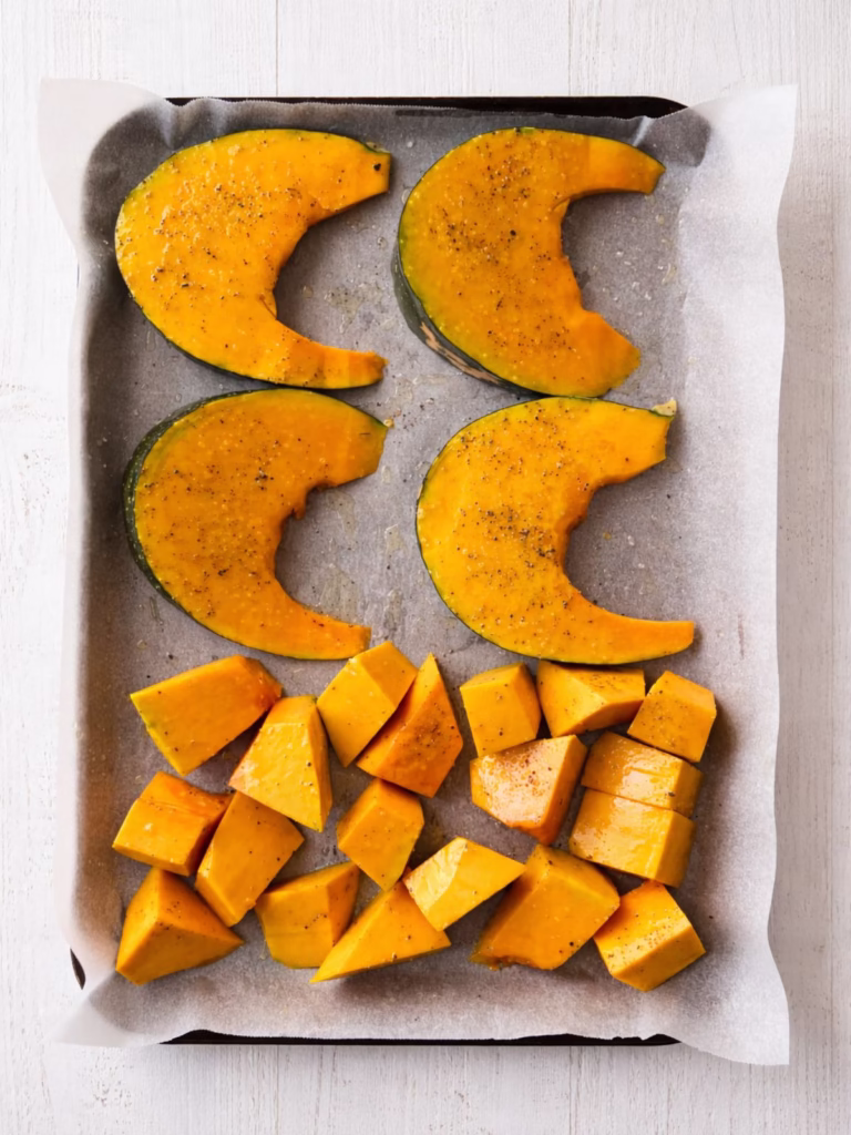 Pumpkin wedges and chunks on a tray ready for roasting with olive oil, salt and pepper