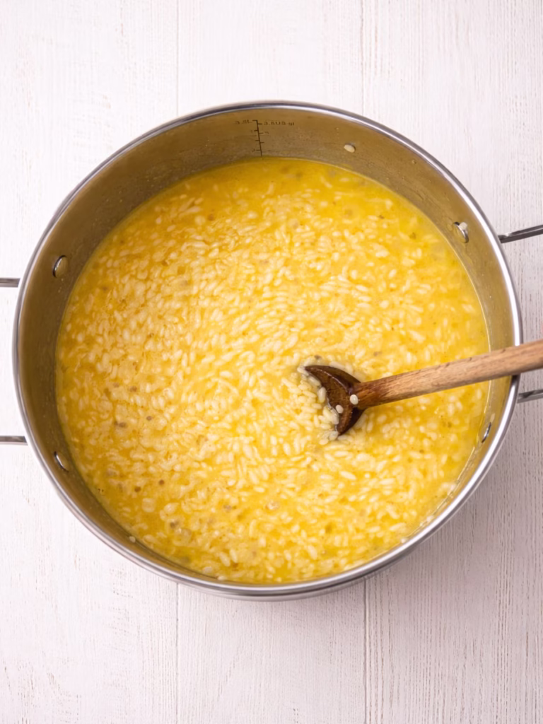 Arborio rice cooking in stock in a pot, showing the creamy risotto texture forming