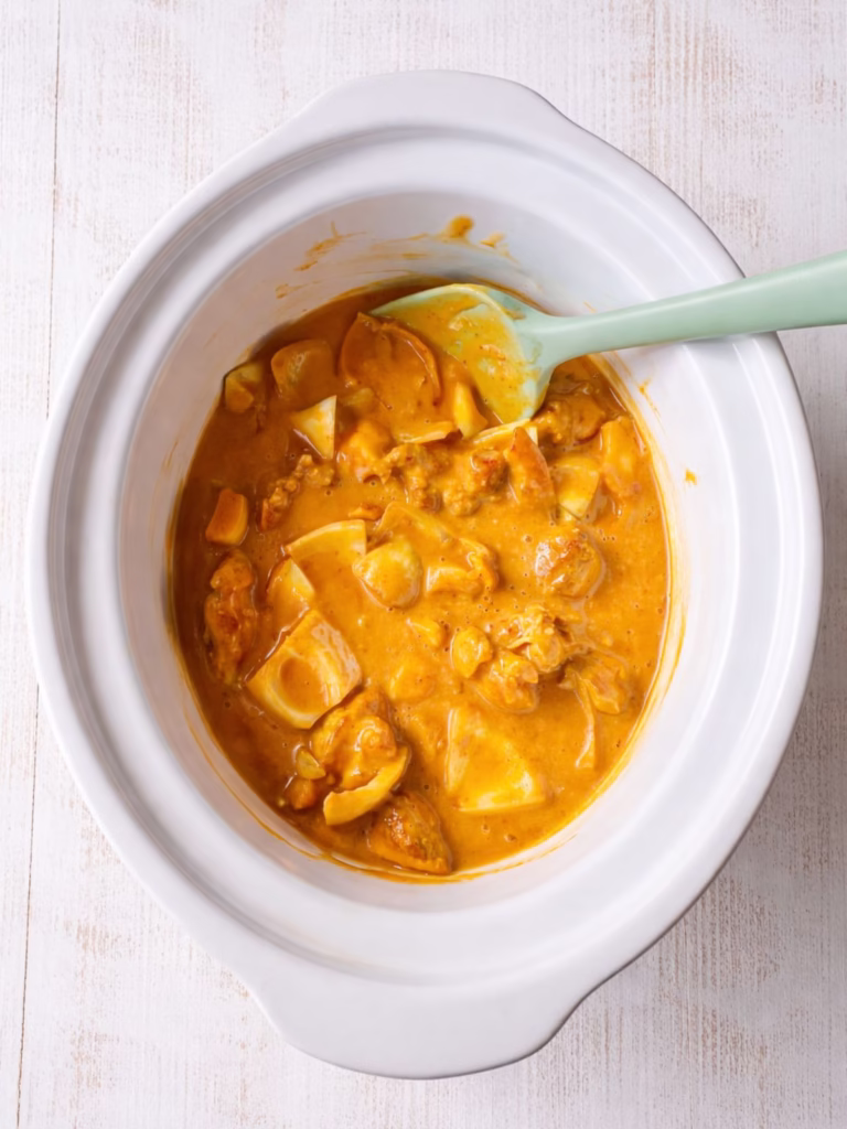Chicken and onion coated in satay sauce in slow cooker before cooking
