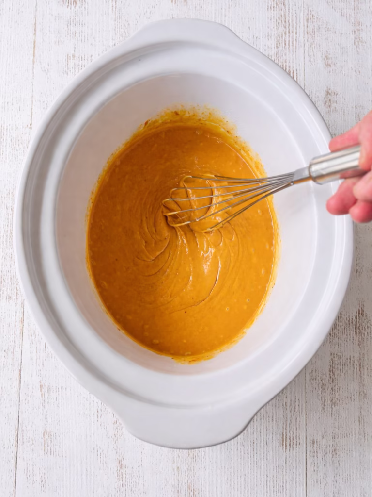 Mixing satay sauce in slow cooker with coconut cream, peanut butter and curry paste