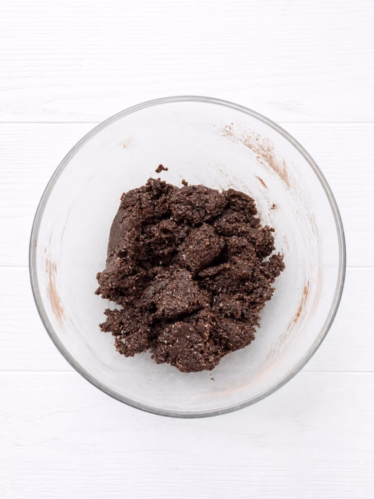Chocolate base mixture in a bowl showing damp sand texture ready to press into tin