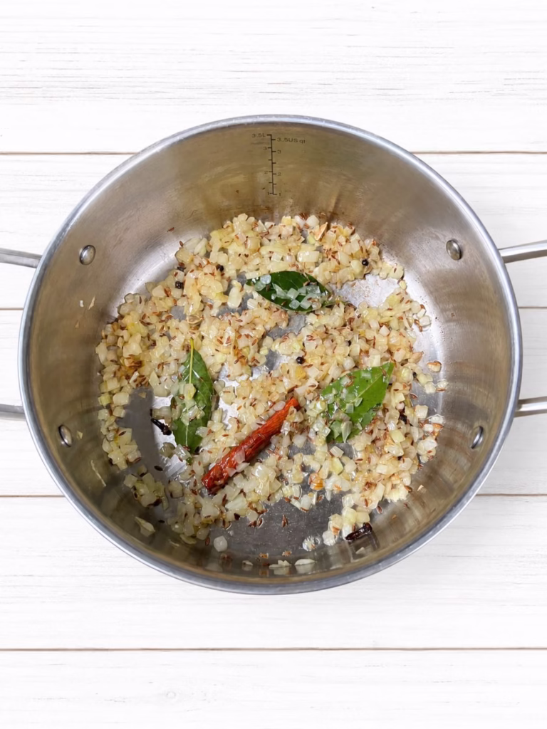 Finely chopped onion cooking in oil with whole spices