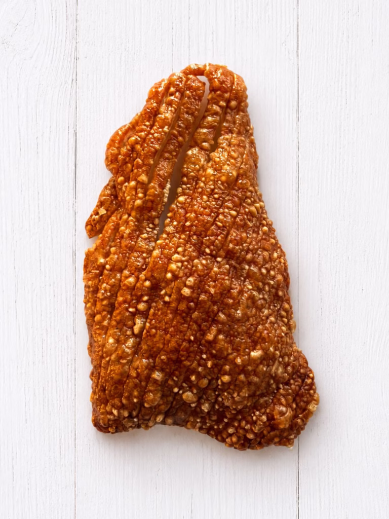 Crispy pork crackle skin on white timber background