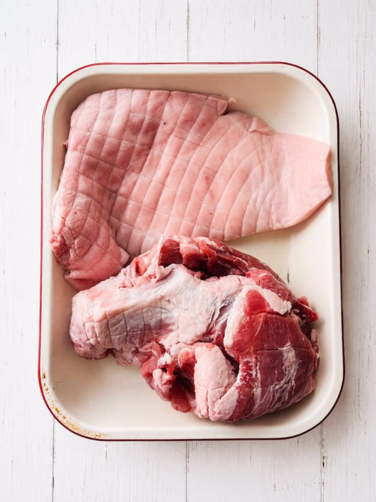 Pork shoulder with the skin removed in a baking dish ready for seasoning for slow cooker pulled pork.